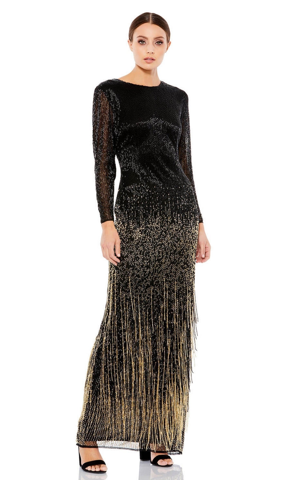 A woman wears the Mac Duggal 93584 Gold-Fringe Black Formal Dress, a long black evening gown with gold sequin details and fringe, styled with black heeled sandals.